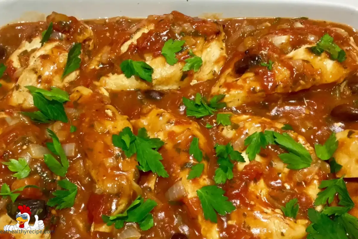 A skillet of golden-brown Chicken Provencal topped with tomatoes and fresh herbs.