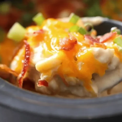 Crock Pot Crack Chicken Casserole with melted cheese, crispy bacon, and green onions in a slow cooker.